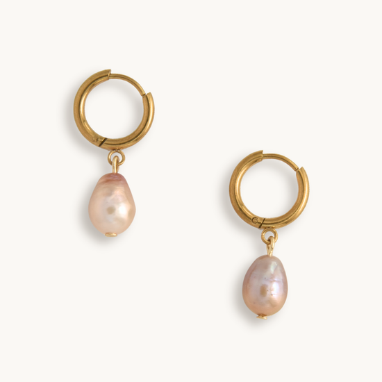 Gold hoop earrings with pink pearl drops on a white background