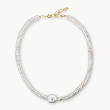 A delicate necklace made of small, tightly packed white beads with a single larger white shell pendant and a gold clasp, shown on a light cream background.