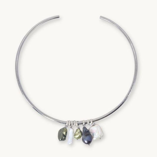 A silver-toned open hoop necklace with five dangling baroque pearl charms in various colors, displayed on a clean off-white background.