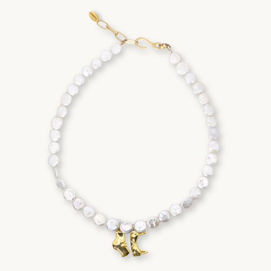 Freshwater coin pearl necklace with a gold bikini top and bottom charm and a gold hook clasp.