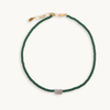 Green beaded necklace with a pearl pendant on a white background