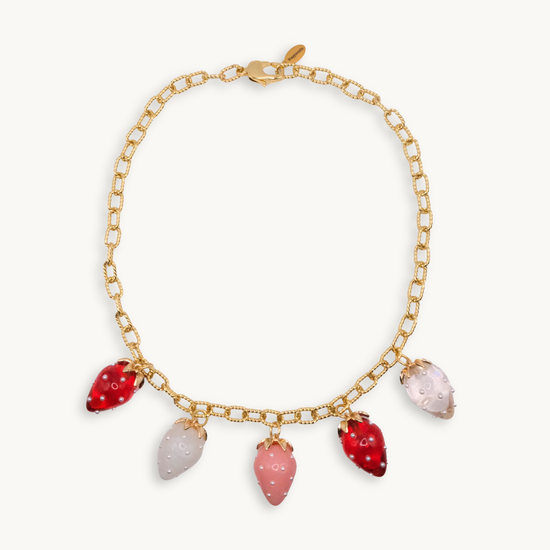 A gold chain necklace with five glass charms shaped like strawberries in red, pink, and white hues, creating a playful and elegant look.