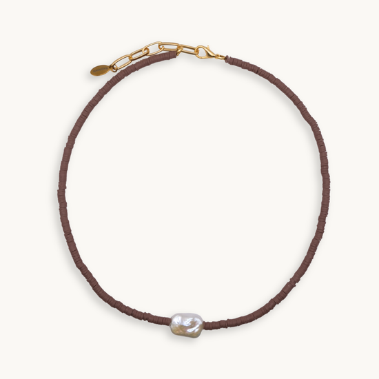 Brown beaded necklace with a pearl pendant on a white background