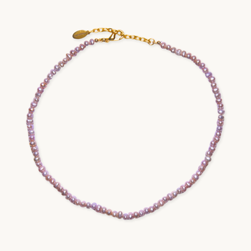 A delicate necklace featuring small, lustrous pink pearls strung along its length, with a gold chain and clasp, set against a plain white background.
