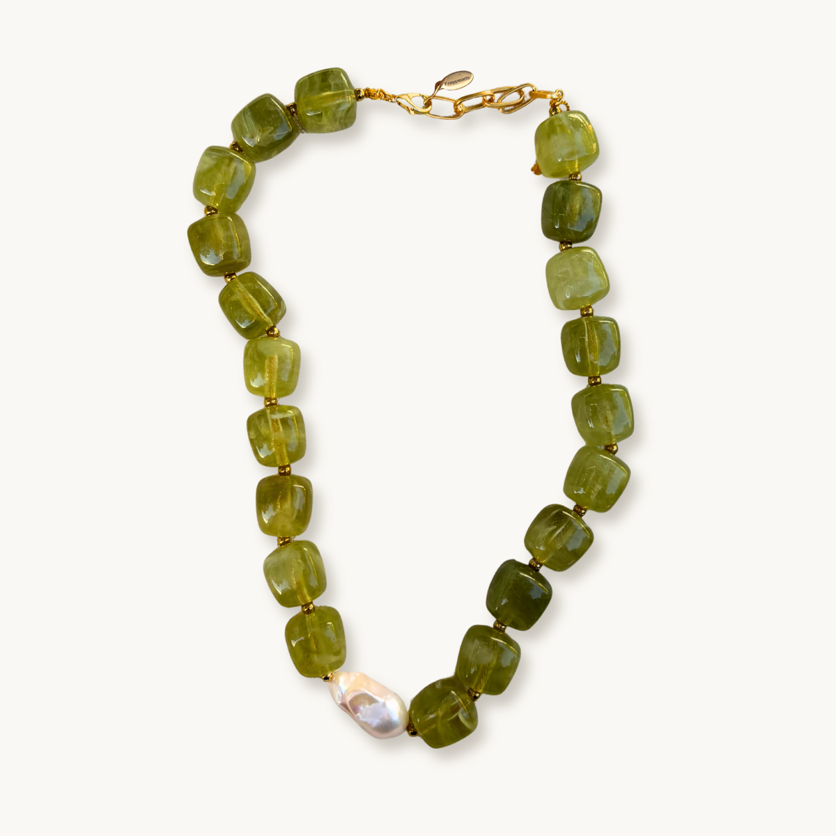 Green gemstone necklace with square beads, featuring a single irregular white pearl. Gold clasps add elegance against a plain white background.