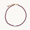 Purple beaded necklace with a pearl pendant on a white background