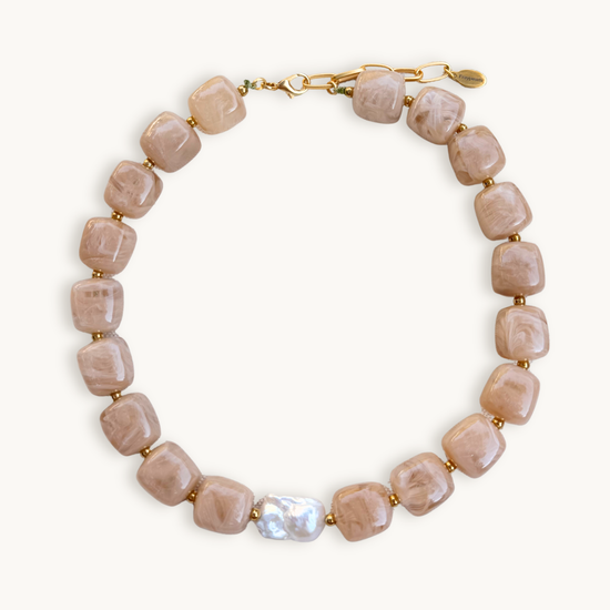 Sand gemstone necklace with square beads, featuring a single irregular white pearl. Gold clasps add elegance against a plain white background.