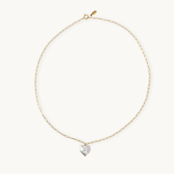 A delicate gold chain necklace with an elongated link design, featuring a shiny heart pearl pendant at the center, against a plain light background.