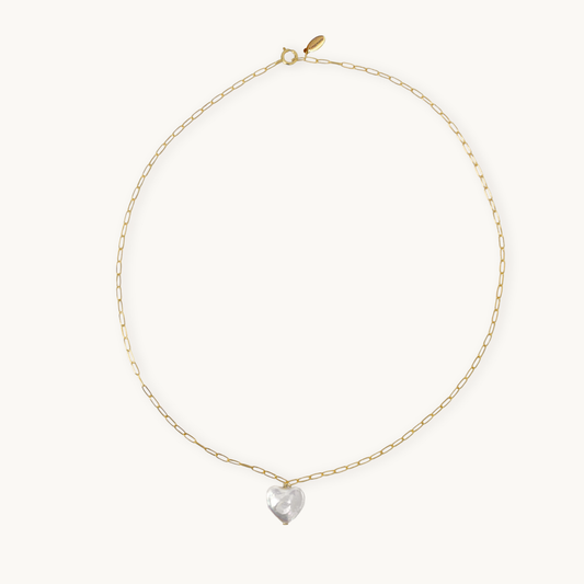 A delicate gold chain necklace with an elongated link design, featuring a shiny heart pearl pendant at the center, against a plain light background.