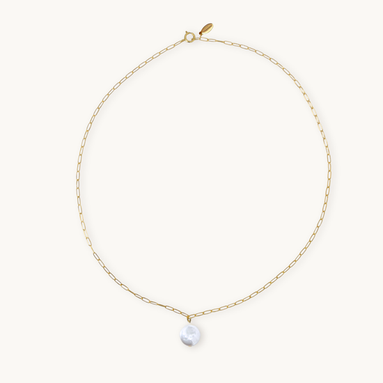 A delicate gold chain necklace with an elongated link design, featuring a shiny round pearl pendant at the center, against a plain light background.