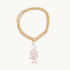 A long gold necklace features an elegant pendant with stacked irregular pearls in shades of white, creating a sophisticated and organic aesthetic.
