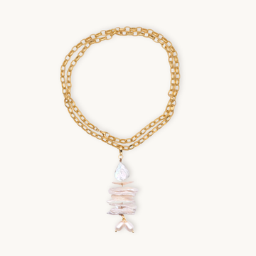 A long gold necklace features an elegant pendant with stacked irregular pearls in shades of white, creating a sophisticated and organic aesthetic.