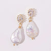Elegant pearl drop earrings with gold accents and sparkling oval gems, set against a soft white background, convey luxury and sophistication.