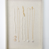 Elegant jewelry display with delicate gold chains and pearl accents lies on a beige fabric background, creating a sophisticated and minimalist aesthetic.
