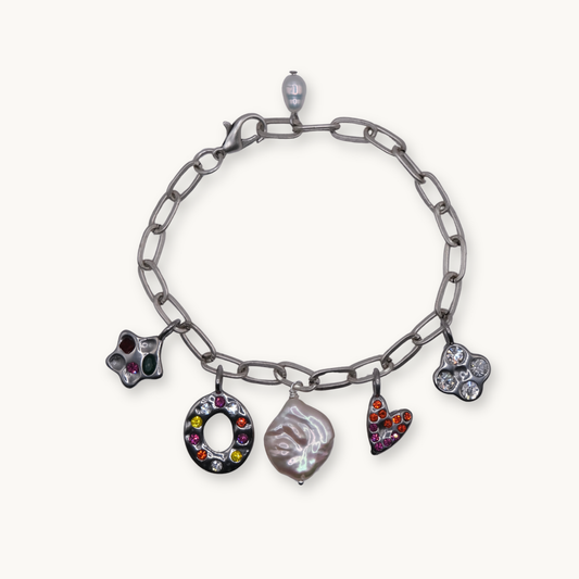 Silver chain bracelet with five colorful charms: a star, circle, pearl, heart, and clover. Each charm is adorned with vibrant, multicolored gems.