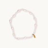 A delicate white pearl bracelet featuring irregularly shaped beads and a small gold tag with engraved text. The tone is elegant and timeless.